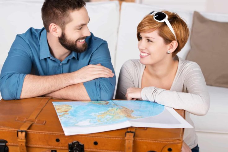 Young happy couple planning a travel with map