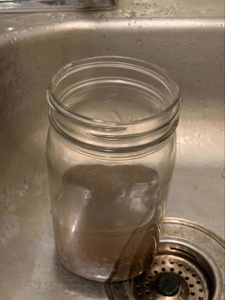 Jar filled with dirty water on top of sink.