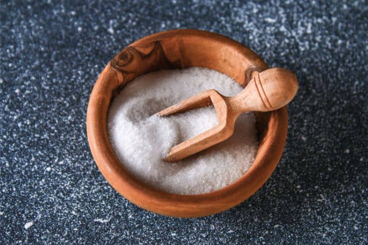 Salt being measured with a wooden spoon